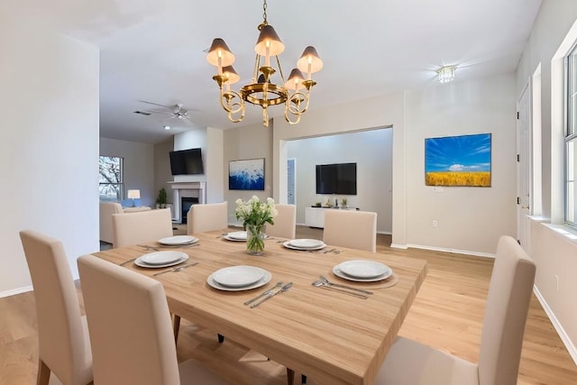 dining area featuring ceiling fan with notable chandelier and light wood-type flooring