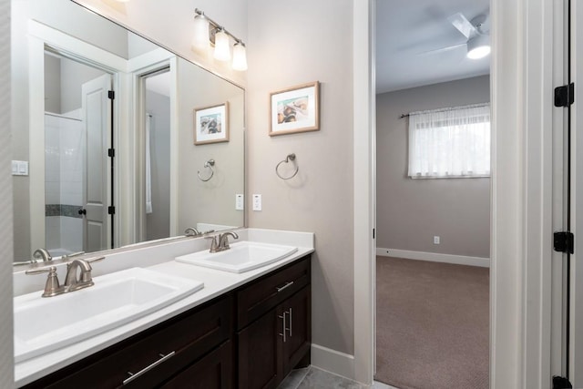 full bathroom with double vanity, a shower, baseboards, and a sink