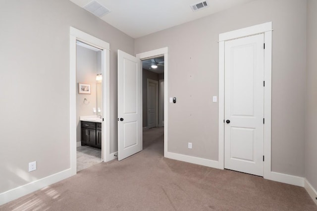 unfurnished bedroom featuring visible vents, connected bathroom, baseboards, light carpet, and a closet