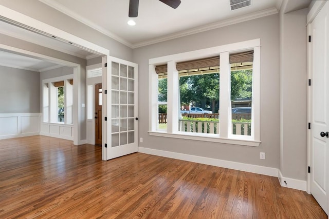 unfurnished room featuring visible vents, wood finished floors, ornamental molding, and a ceiling fan