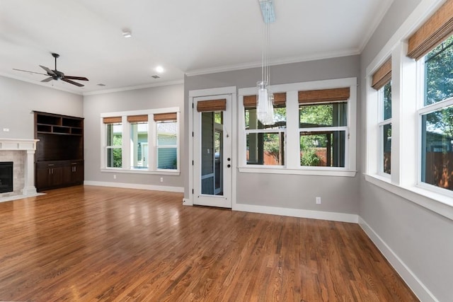 unfurnished living room with wood finished floors, baseboards, and ornamental molding