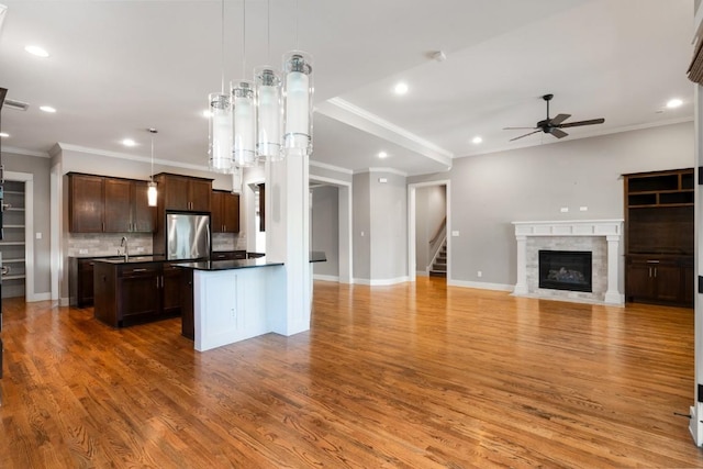 kitchen featuring a center island with sink, a ceiling fan, open floor plan, freestanding refrigerator, and dark brown cabinetry