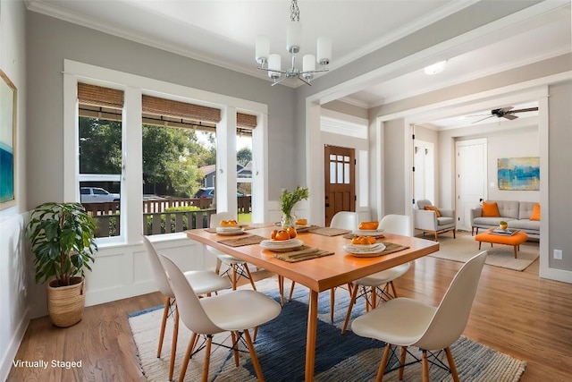 dining area featuring wood finished floors, crown molding, and ceiling fan with notable chandelier