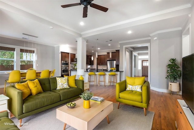 living room featuring crown molding, ceiling fan, dark wood-type flooring, and ornate columns