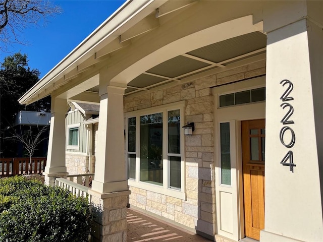 doorway to property featuring stone siding and covered porch