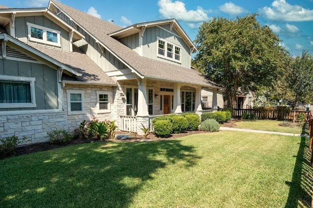 view of front of house featuring a front lawn, board and batten siding, stone siding, and a shingled roof