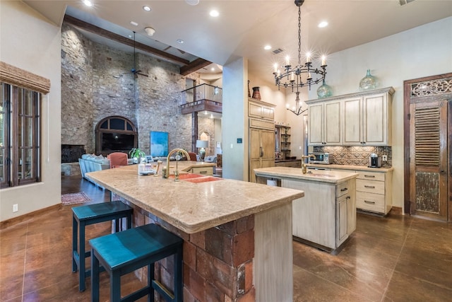 kitchen with an island with sink, decorative light fixtures, cream cabinetry, a high ceiling, and a breakfast bar