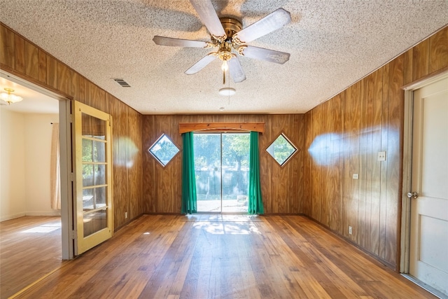 spare room featuring wood walls, wood-type flooring, and ceiling fan