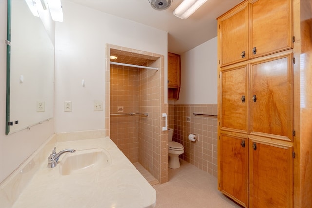 bathroom featuring a tile shower, vanity, tile walls, tile patterned floors, and toilet