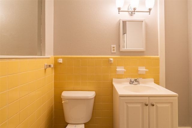 bathroom featuring vanity, tile walls, and toilet