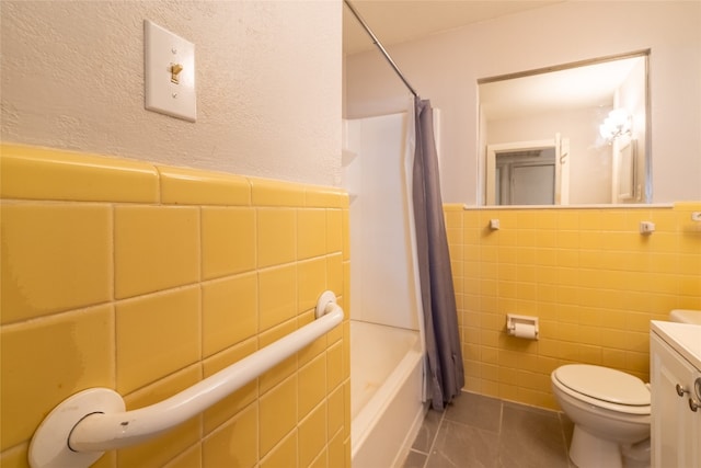 full bathroom featuring toilet, shower / bath combo with shower curtain, tile patterned floors, tile walls, and vanity