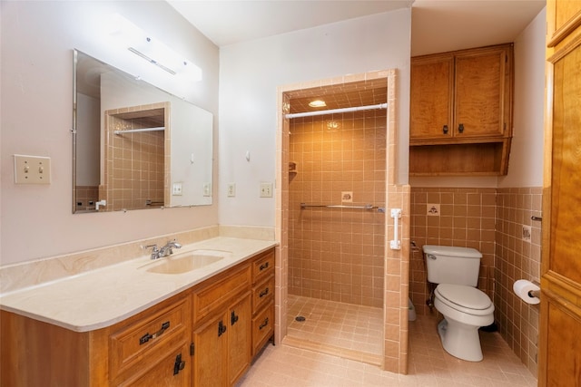 bathroom with a tile shower, vanity, tile walls, tile patterned floors, and toilet