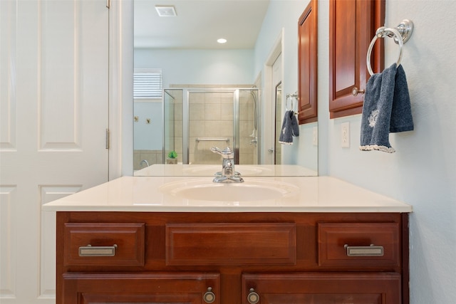 bathroom featuring a shower with shower door and vanity