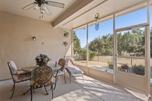 unfurnished sunroom featuring beam ceiling, a healthy amount of sunlight, and ceiling fan