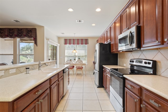 kitchen with stainless steel appliances, sink, decorative light fixtures, light tile patterned floors, and backsplash