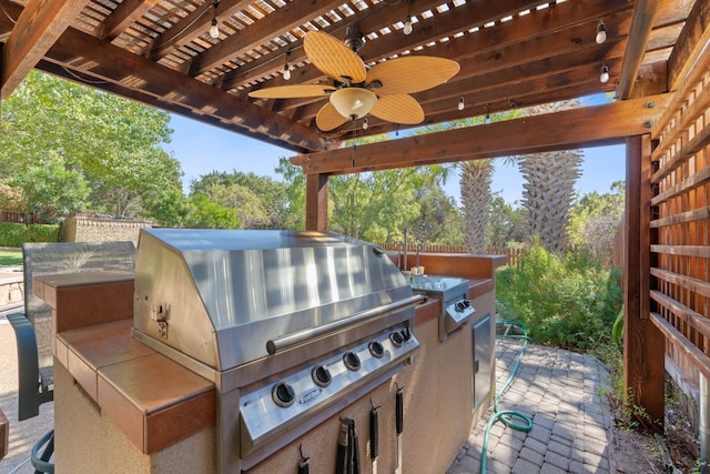 view of patio featuring ceiling fan, grilling area, an outdoor kitchen, and a pergola