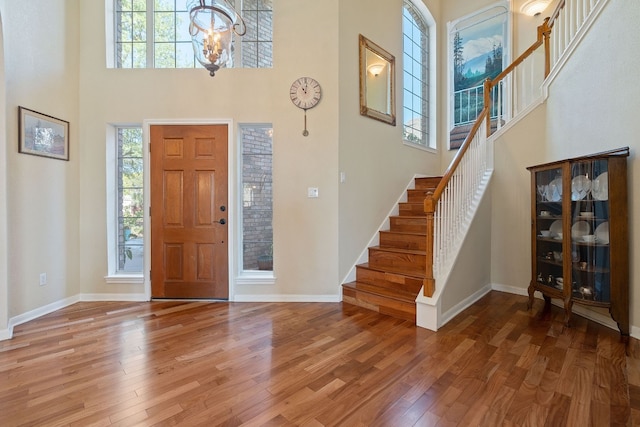 foyer entrance with hardwood / wood-style flooring, a notable chandelier, and a towering ceiling