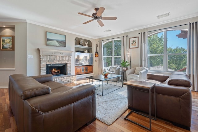 living room featuring hardwood / wood-style flooring, crown molding, built in features, and a fireplace