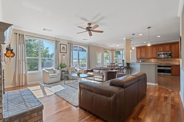 living room featuring ceiling fan, light wood-type flooring, and crown molding