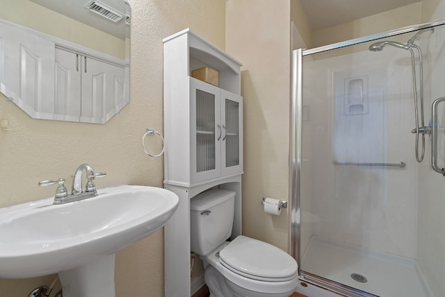 bathroom with an enclosed shower, sink, and toilet