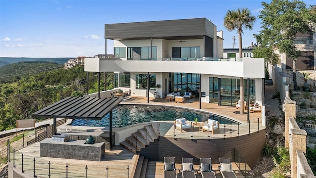 6809 Oasis Pass, Austin, TX 78732 - rear view of property featuring a balcony, an infinity pool, a patio area, stucco siding, and an outdoor hangout area