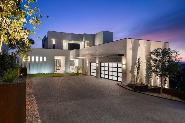 contemporary house with a garage, stucco siding, and decorative driveway