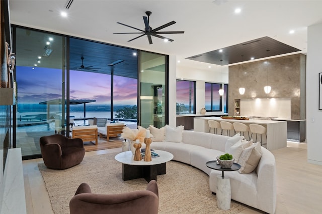 living room featuring a water view, expansive windows, and light wood-type flooring