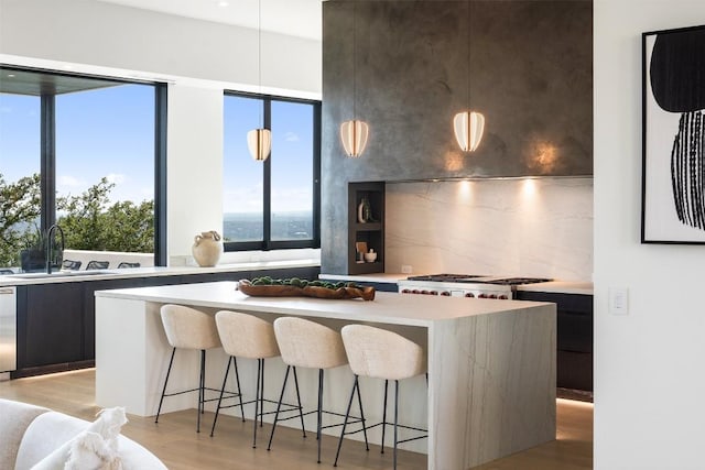 kitchen with a breakfast bar, light countertops, a sink, modern cabinets, and a center island