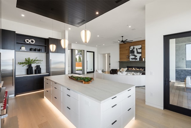 kitchen featuring hanging light fixtures, stainless steel built in refrigerator, white cabinetry, and a large island