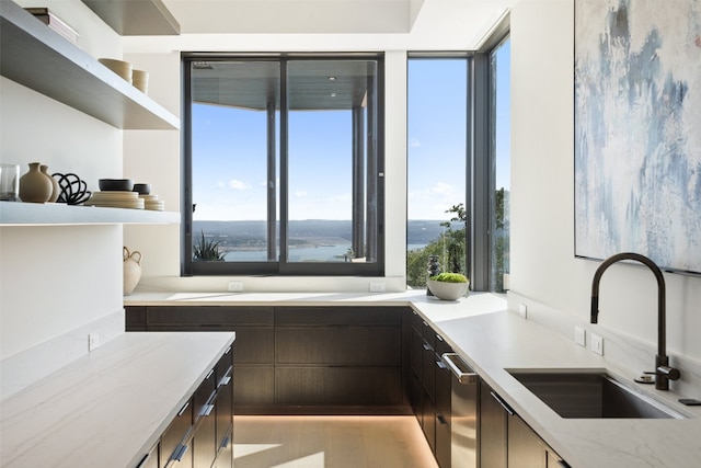 kitchen featuring dark brown cabinets, dishwasher, sink, and a water view