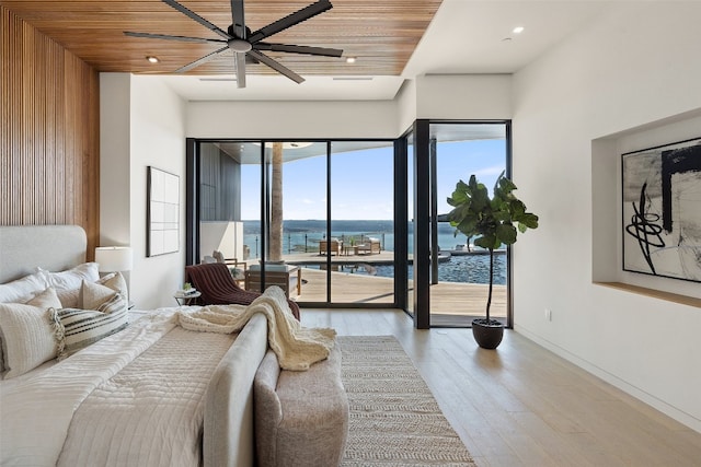 bedroom with ceiling fan, wood ceiling, light hardwood / wood-style flooring, access to exterior, and a water view