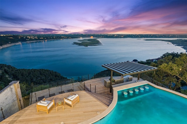 pool at dusk featuring a water view