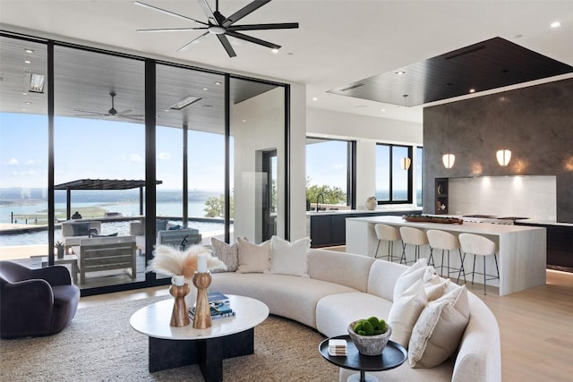6809 Oasis Pass, Austin, TX 78732 - living area with a water view, expansive windows, light wood-style flooring, a ceiling fan, and recessed lighting
