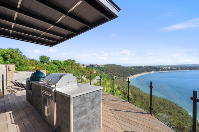 wooden terrace featuring area for grilling, grilling area, and a water view