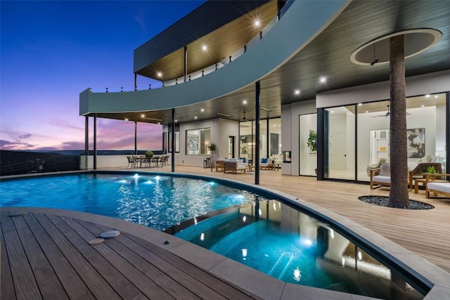 6809 Oasis Pass, Austin, TX 78732 - pool at dusk featuring a wooden deck, outdoor lounge area, a pool with connected hot tub, and a ceiling fan