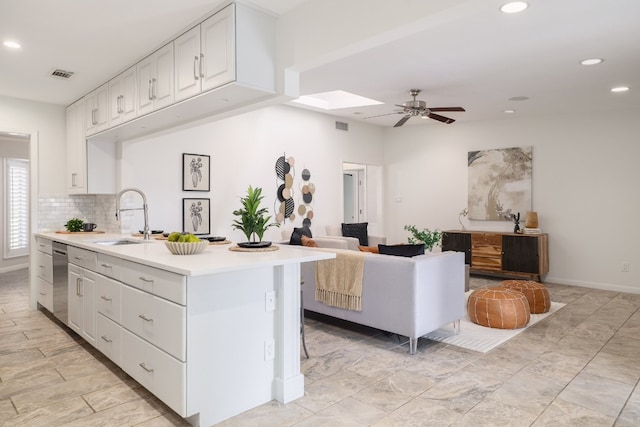 kitchen featuring ceiling fan, sink, tasteful backsplash, stainless steel dishwasher, and white cabinetry