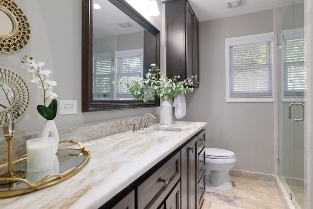 bathroom featuring a shower with shower door, vanity, and toilet