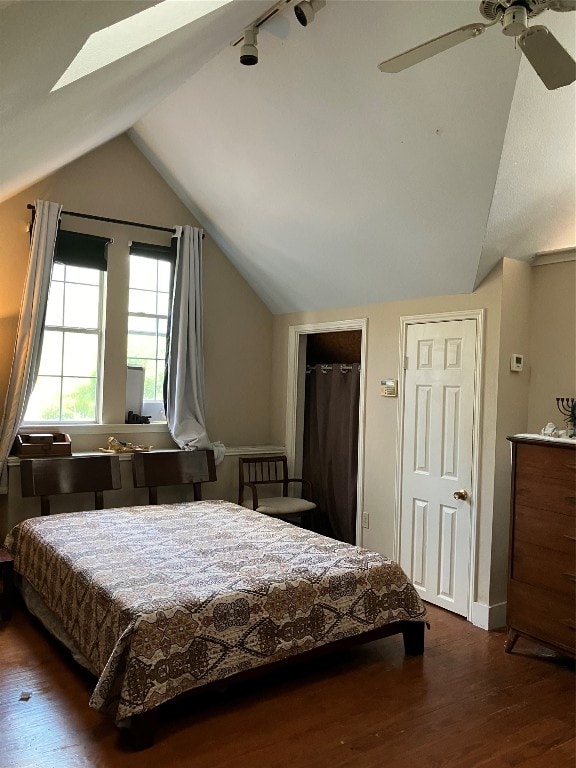 bedroom with ceiling fan, dark hardwood / wood-style floors, and lofted ceiling with skylight