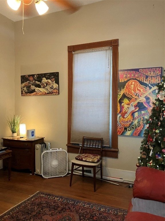 living area with wood-type flooring and ceiling fan