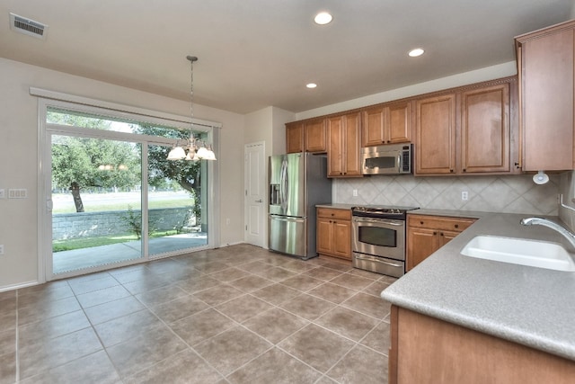 kitchen featuring light tile patterned floors, sink, decorative light fixtures, a chandelier, and appliances with stainless steel finishes