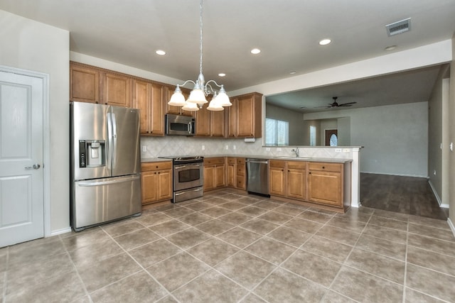 kitchen with sink, tasteful backsplash, decorative light fixtures, appliances with stainless steel finishes, and ceiling fan with notable chandelier