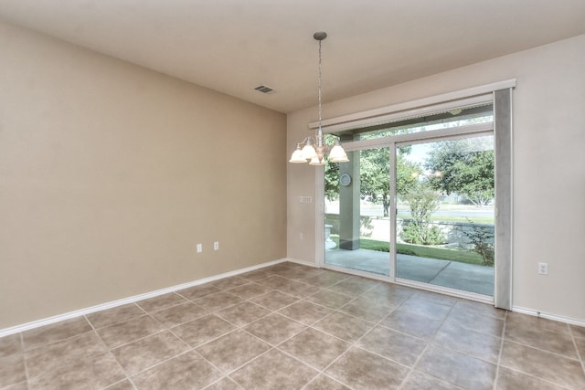 spare room with tile patterned floors and an inviting chandelier