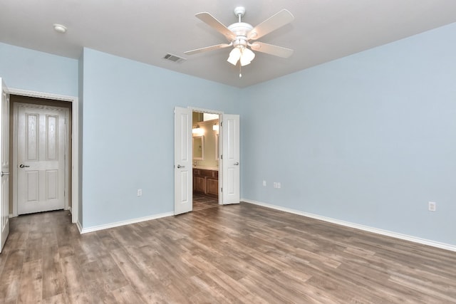 unfurnished bedroom with ensuite bath, ceiling fan, and wood-type flooring