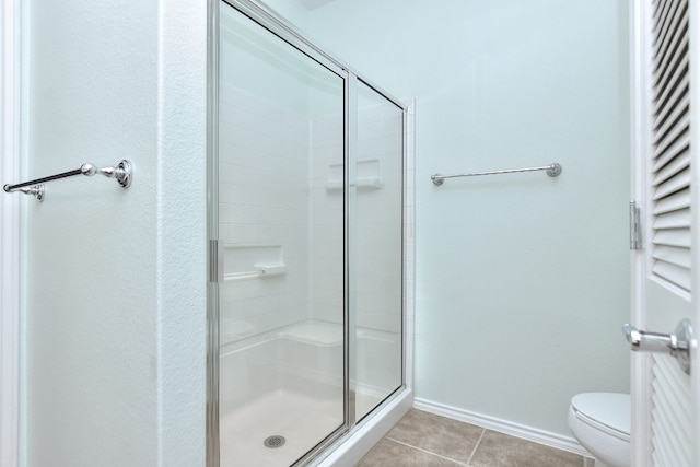 bathroom featuring tile patterned floors, a shower with door, and toilet