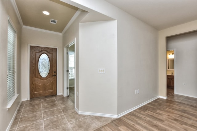 entryway with light hardwood / wood-style floors and ornamental molding