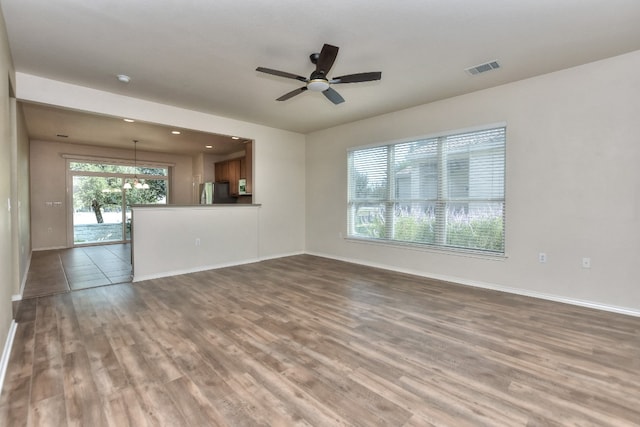 unfurnished living room featuring ceiling fan with notable chandelier and hardwood / wood-style floors