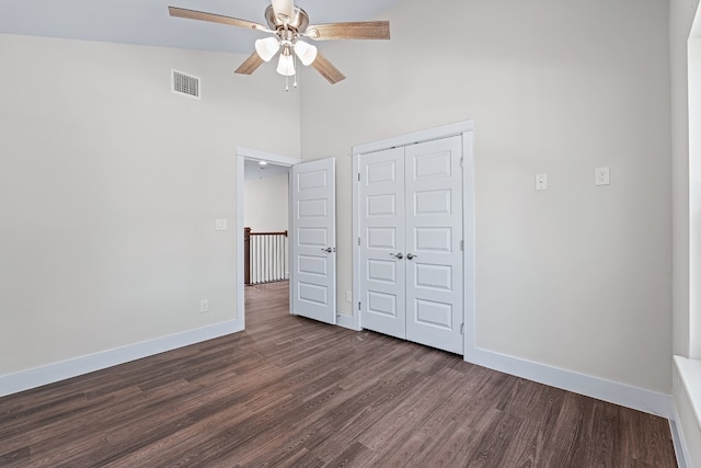 unfurnished bedroom with ceiling fan, dark hardwood / wood-style floors, a closet, and high vaulted ceiling