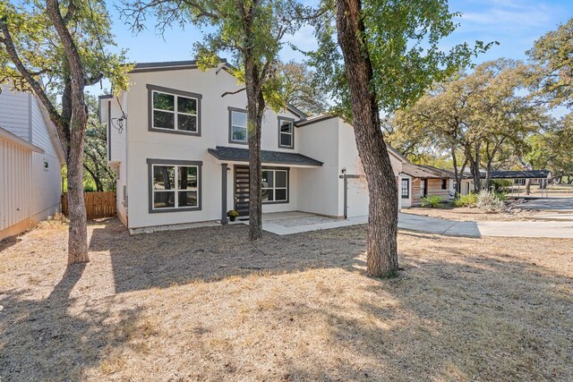 110 E Holland St, San Marcos, TX 78666 - view of front of house featuring stucco siding, concrete driveway, a patio, and an attached garage