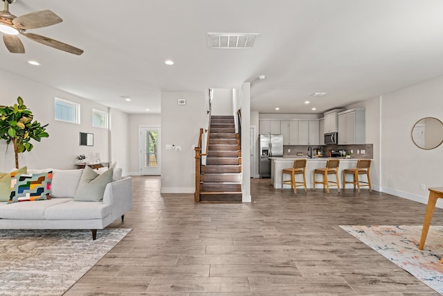110 E Holland St, San Marcos, TX 78666 - living room with baseboards, recessed lighting, light wood-style floors, ceiling fan, and stairway