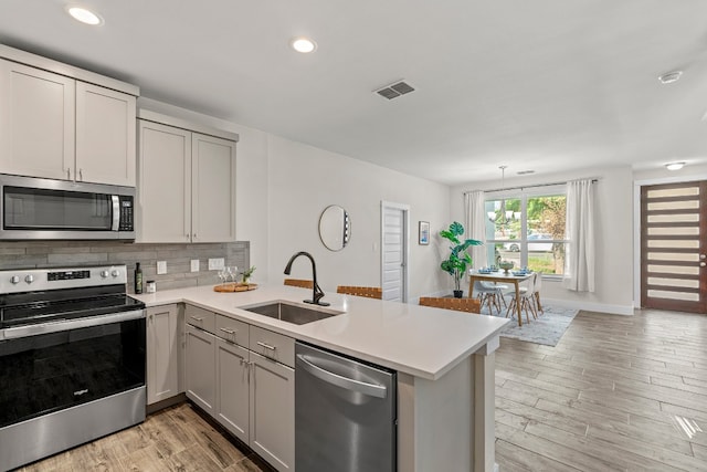 110 E Holland St, San Marcos, TX 78666 - kitchen with stainless steel appliances, a sink, a peninsula, light countertops, and recessed lighting